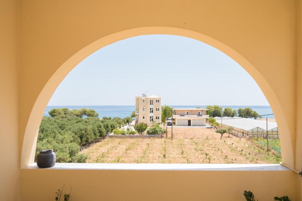 an arched window with a view of a field at Eden of grameno Luxury sea view apartment in Palaiochora