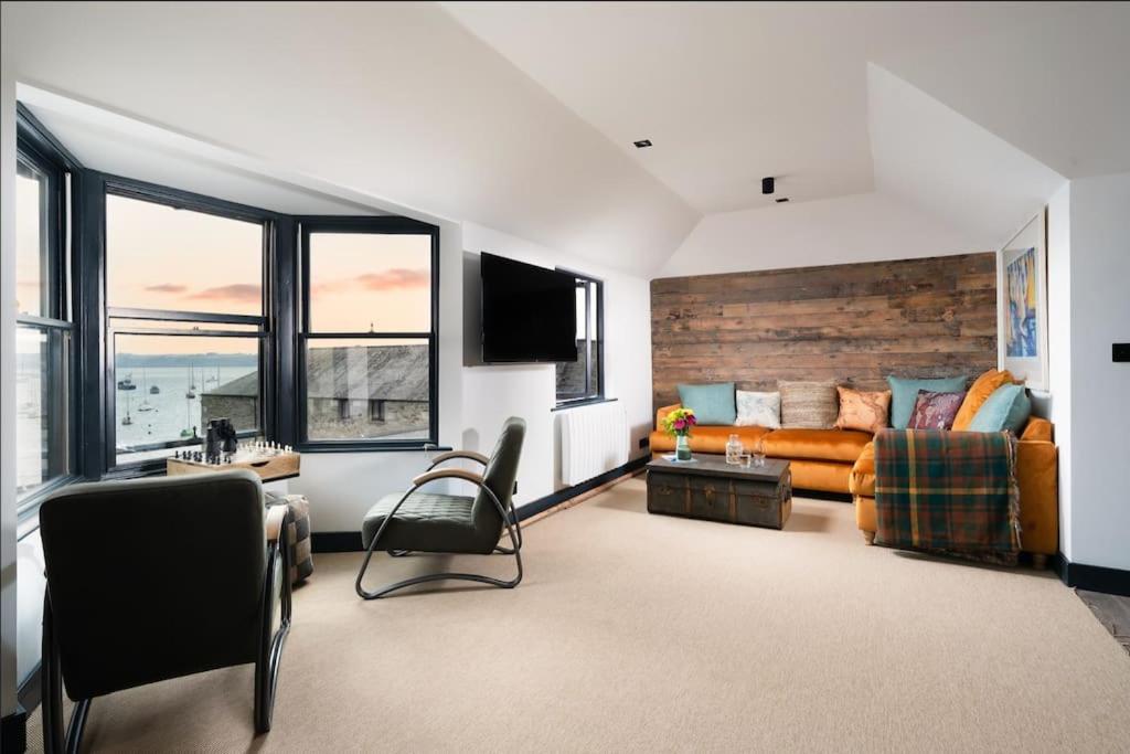 a living room with a bed and a couch and windows at CAPTAINS LOFT in Falmouth