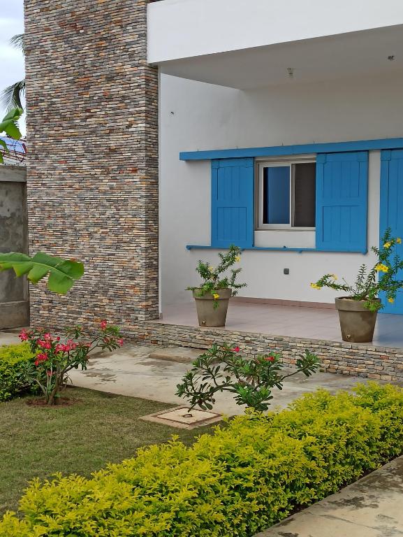 una casa con puertas azules y algunas plantas en Chez Fèmi, route des pêches, en Cotonou
