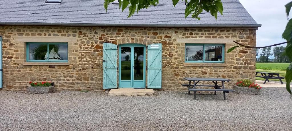 un edificio con una puerta azul y una mesa de picnic en Gite Le Mascaret, en Roz-sur-Couesnon