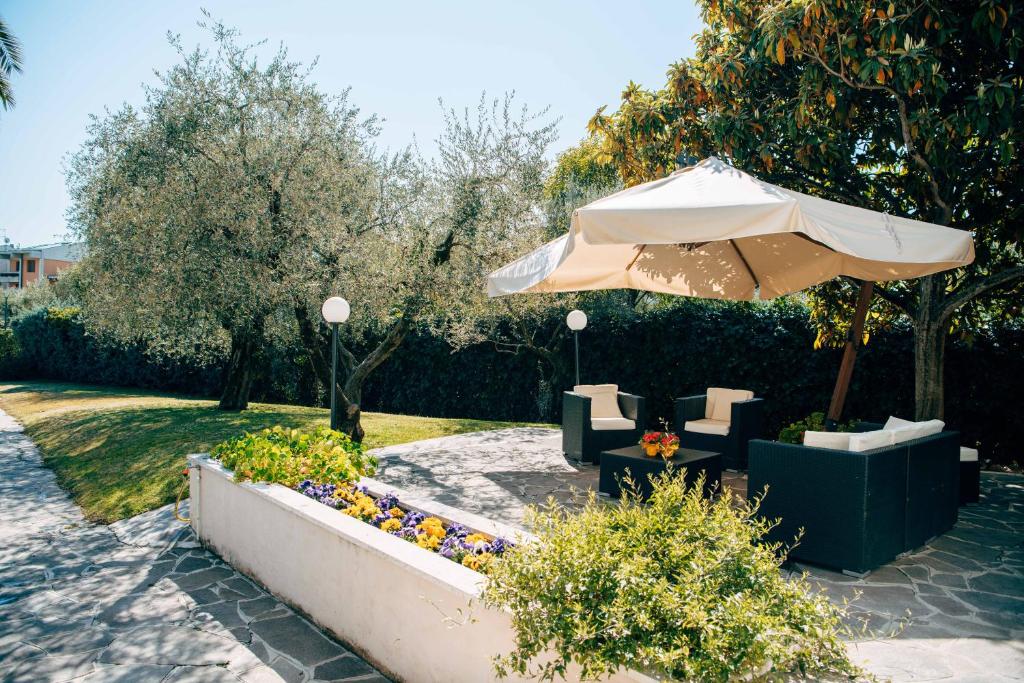 a patio with an umbrella and chairs and flowers at Villa Angela Olympic Garda Lake in Toscolano Maderno