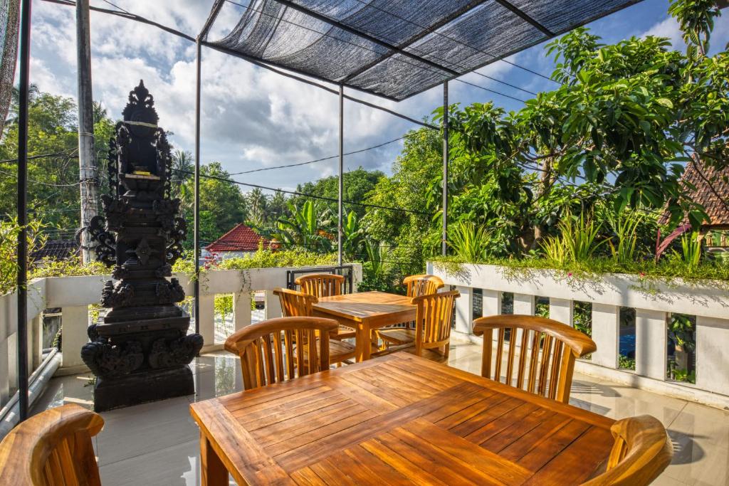a wooden table and chairs on a balcony at L Degus Hostel in Nusa Penida