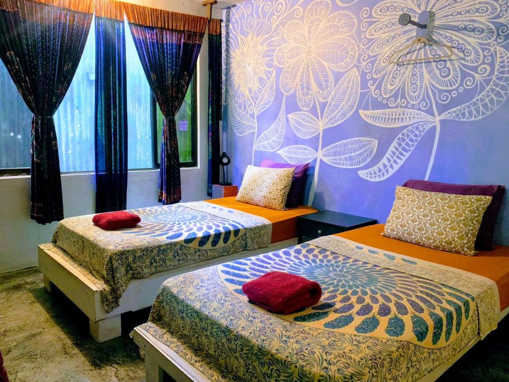 a bedroom with two beds and a wall with a flower mural at Casajungla Hostel in Jacó