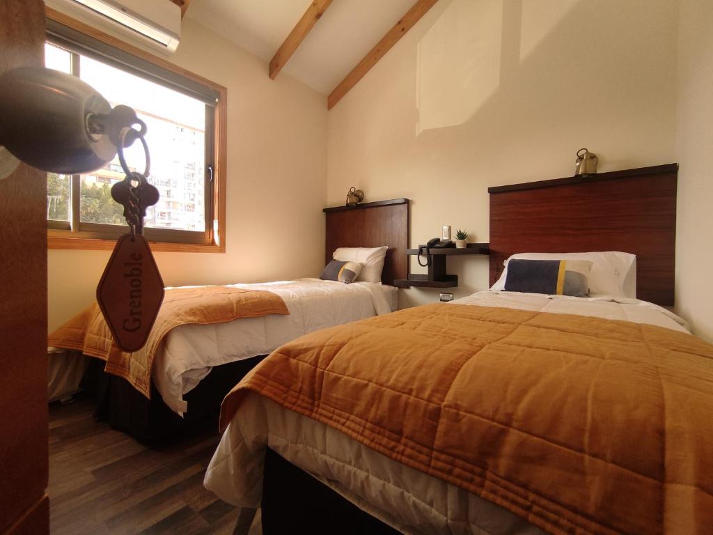 a bedroom with two beds and a window at Hotel Le Petit in Concepción