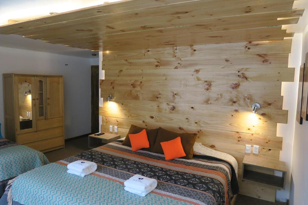 a bedroom with two beds and a wooden wall at CASA SAPANTIANA con vista al bosque, cerca a Sacsayhuaman in Cusco