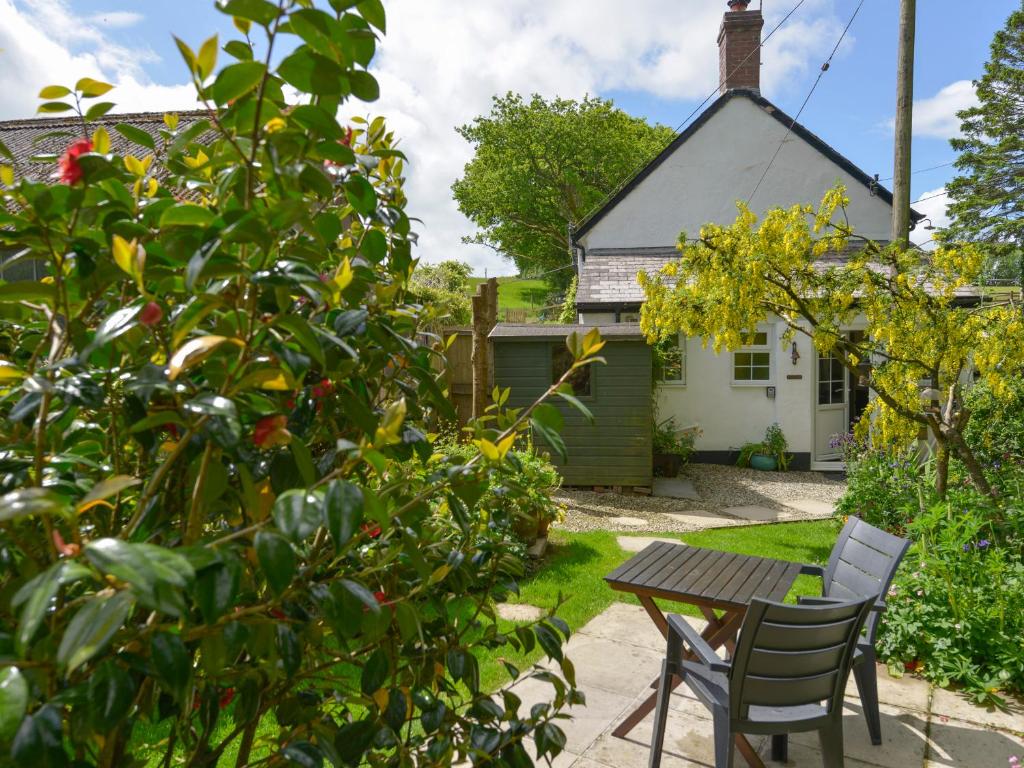 a garden with a table and chairs in front of a house at Little Week Cottage in Bridestowe