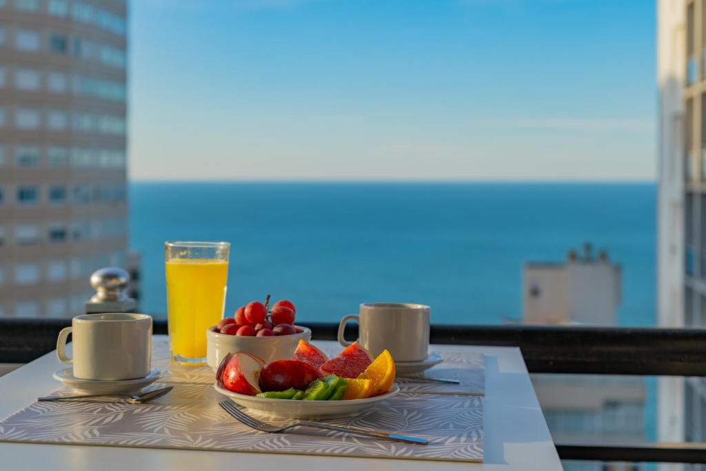 a table with a plate of fruit and a glass of orange juice at Departamento Varese Güemes Alta Gama Luxury 4/5 Pax Vista Mar in Mar del Plata