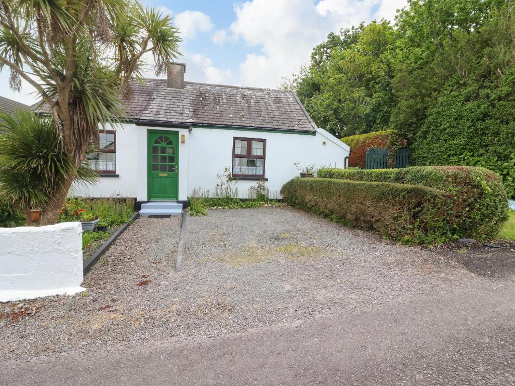 a white house with a green door and a driveway at Brendan's Cottage in Valentia Island
