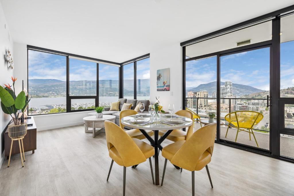 a living room with a table and chairs and windows at Brand New Luxury Downtown Near the Beach #16 in Kelowna