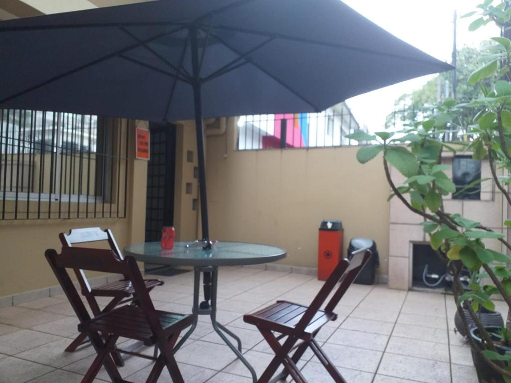 聖保羅的住宿－Orion Hostel Congonhas，天井上配有带2把椅子和遮阳伞的桌子