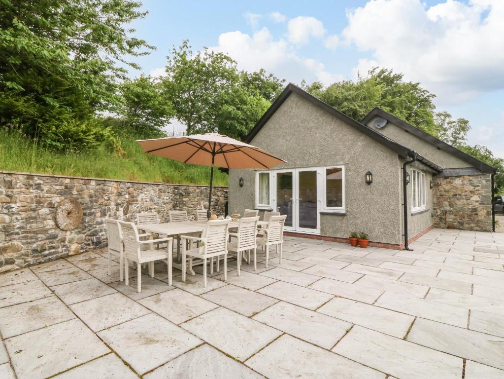 a patio with a table and chairs and an umbrella at Ochr Y Garth in Llanrwst