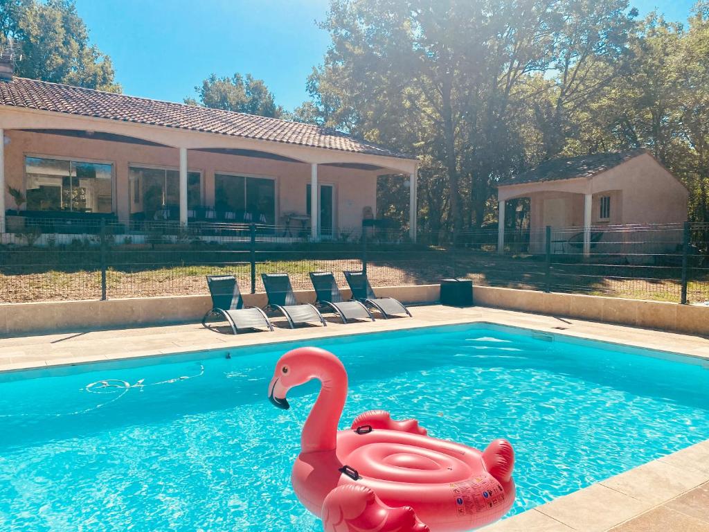 un cygne en plastique rose dans une piscine dans l'établissement Cahors 10 personnes piscine Villa Carpe Diem certifiée 4 étoiles, à Arcambal