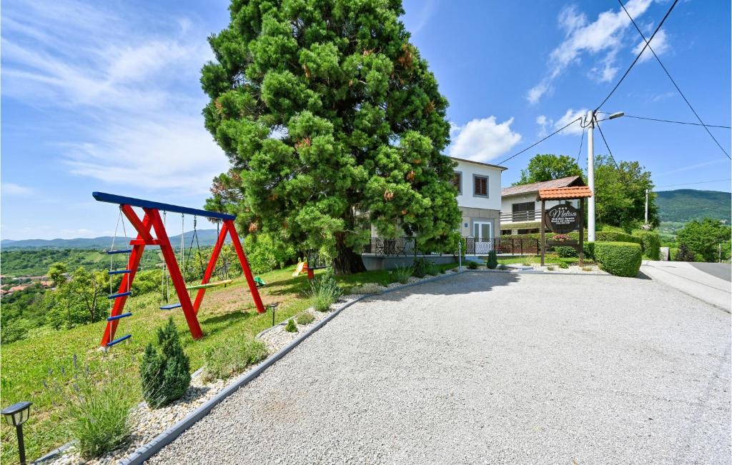 une balançoire rouge sur le côté d'une route devant une maison dans l'établissement Lovely Home In Gornja Reka With Wifi, à Lokošin Dol