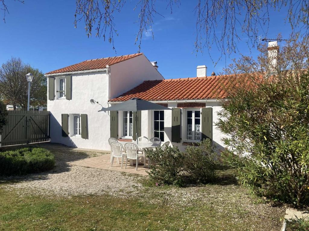 une maison blanche avec une table et des chaises dans l'établissement Maison charmante 6 pers, jardin clos, TV et Wifi, proche commerces et plage, petit chien accepté. - FR-1-224B-165, à LʼÉpine