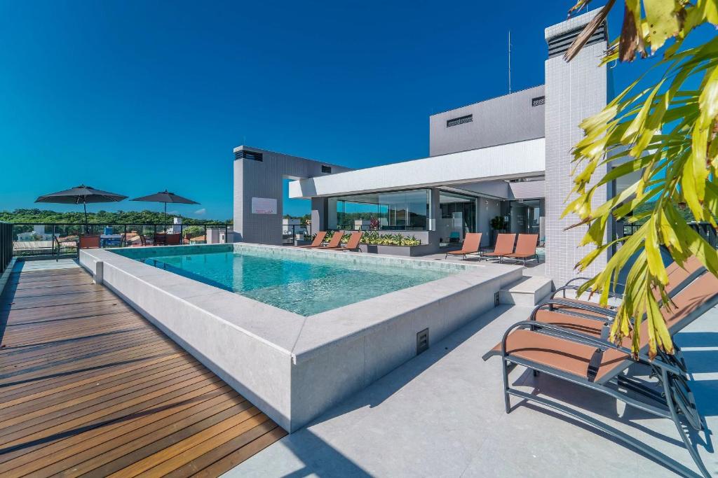 ein Swimmingpool mit Stühlen und ein Haus in der Unterkunft Adra 301 - Apartamento no centro de Bombinhas - Rooftop com piscina e academia - À poucos metros da praia - (Consultar serviços de roupas de cama e banho) in Bombinhas