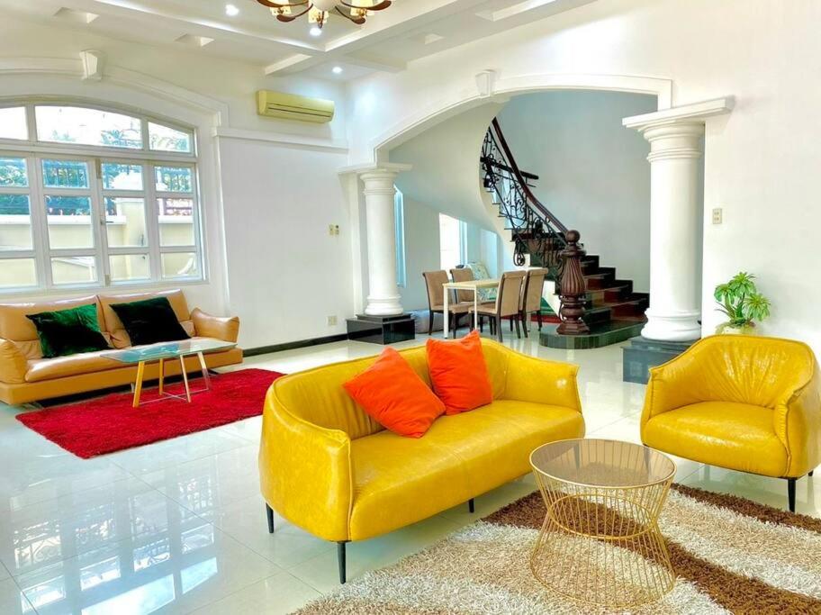a living room with a yellow couch and two chairs at Gem Villa 15, biệt thự 8 phòng ngủ lớn, hồ bơi lớn in Ho Chi Minh City