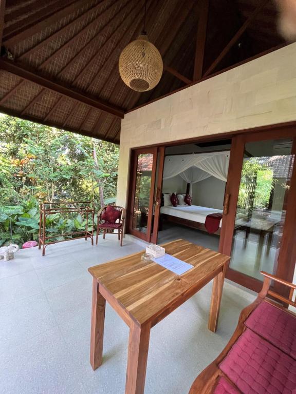 a room with a wooden table and a bed at Sama's Cottages and Villas in Ubud