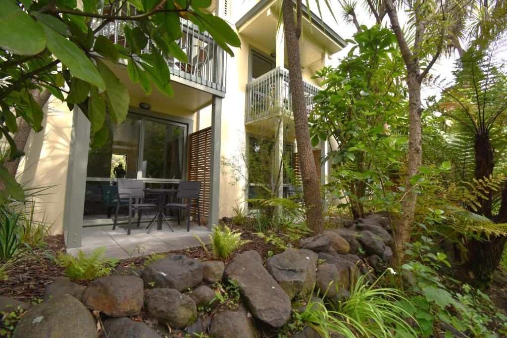 a house with a balcony and a stone wall at La Rochelle Motel in Akaroa