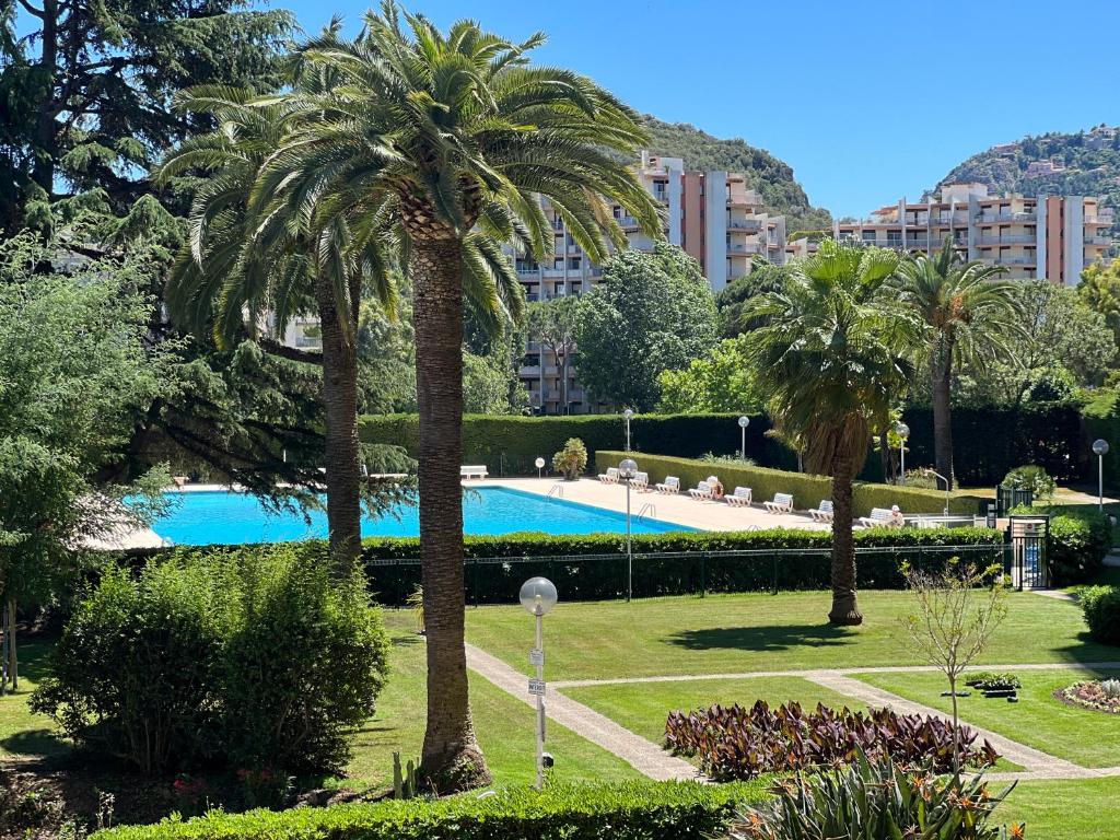 een zwembad in een park met palmbomen en gebouwen bij Cannes Marina Mandelieu in Mandelieu-la-Napoule