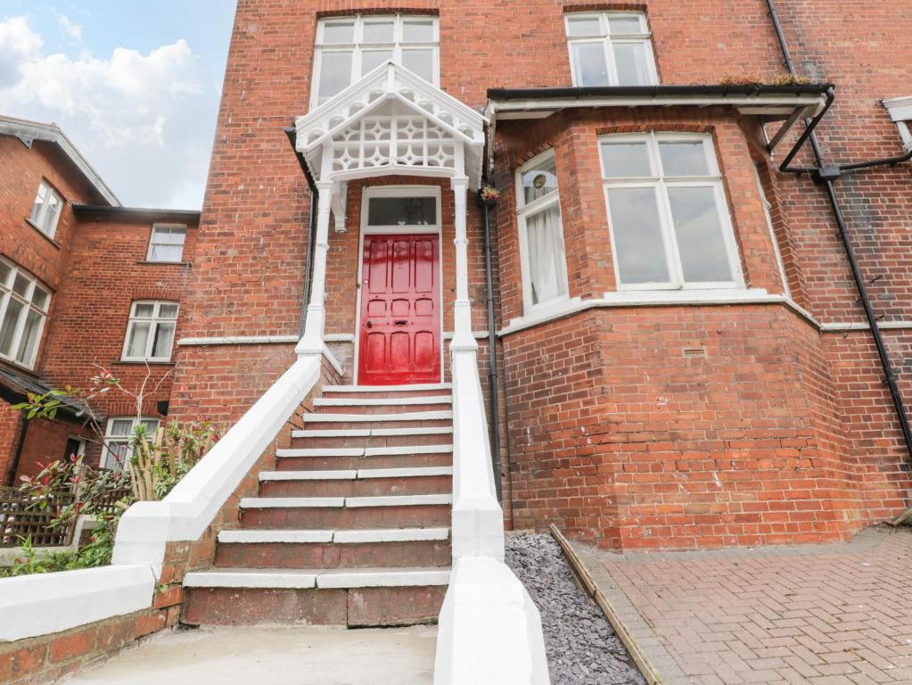 a brick house with a red door and stairs at Pannett Park View in Whitby