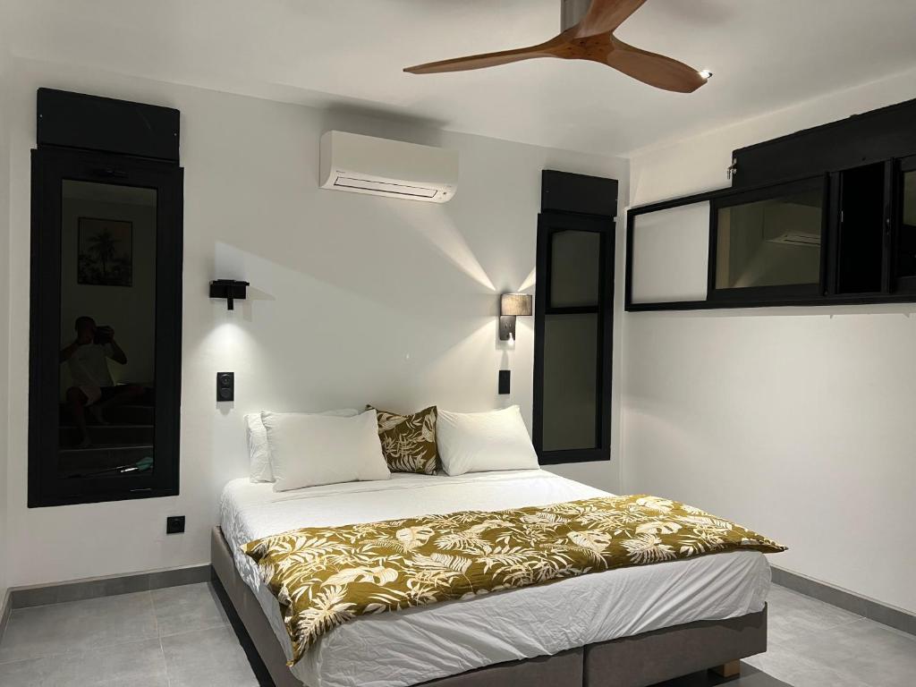 a bedroom with a bed with a ceiling fan at L'Eté sans fin, vue mer in Filaos
