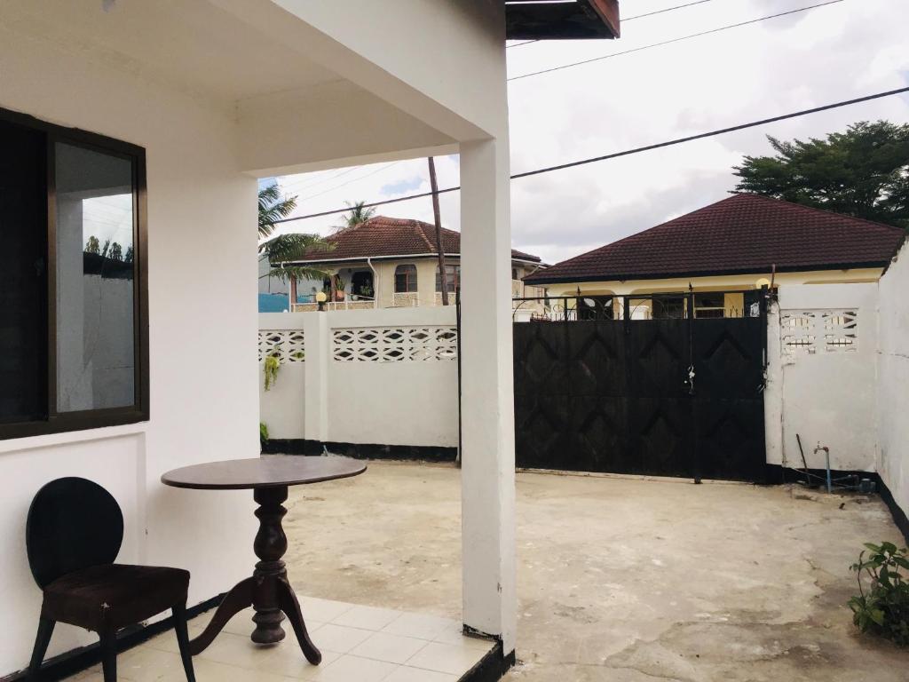 une terrasse avec une table et une chaise ainsi qu'une maison dans l'établissement Mikocheni Home stay, à Dar es Salaam