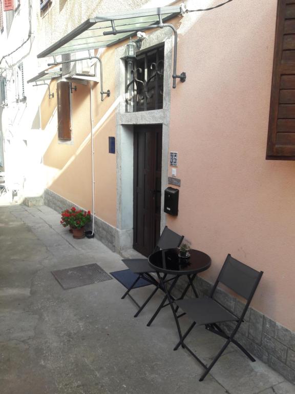 una mesa y sillas junto a un edificio con puerta en Padelica, en Mošćenička Draga