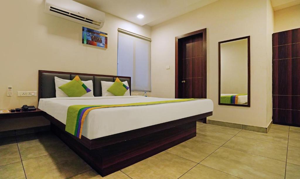 a bedroom with a large bed and a mirror at Treebo Trend Lazystay Grand Patia in Bhubaneshwar