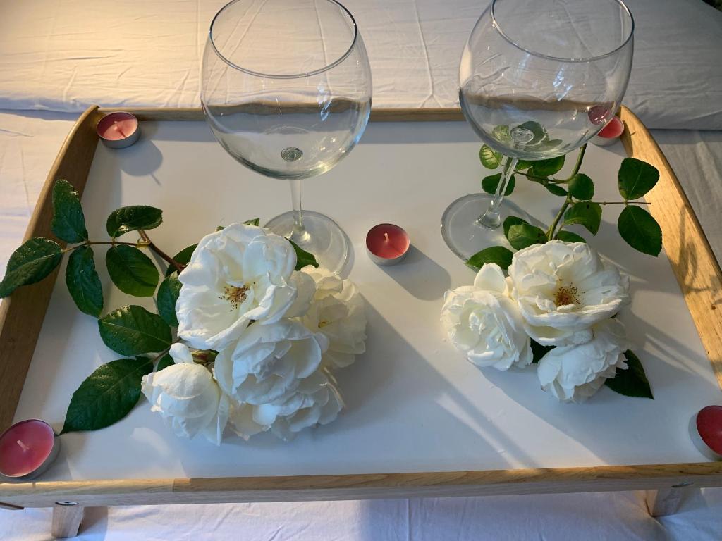 Dois copos de vinho e flores brancas numa bandeja em Glastonbury town center-entire apartment em Glastonbury