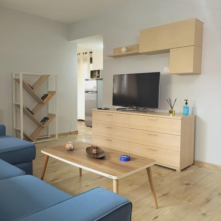 a living room with a tv and a blue couch at Kouros Studios in Kavála