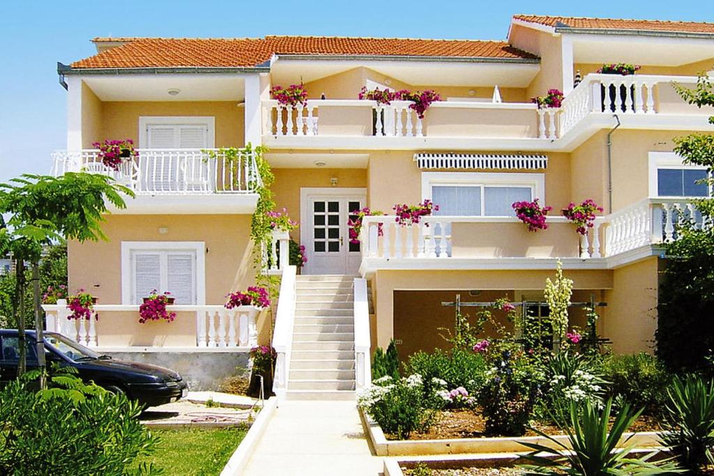 Opatijski Torovi的住宿－Happy Apartments, Biograd，白色阳台和粉红色鲜花的房子