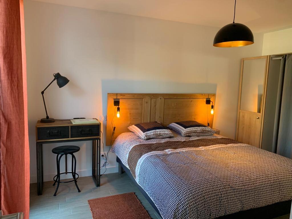 ein Schlafzimmer mit einem Bett und einem Tisch mit einer Lampe in der Unterkunft Le moulin des sables, maison rétaise. in La Flotte