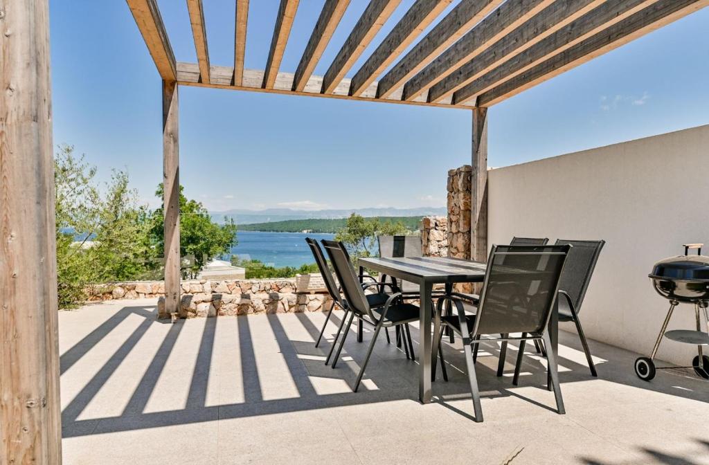 un patio con mesa, sillas y parrilla en Apartment Flori with sea view, en Malinska
