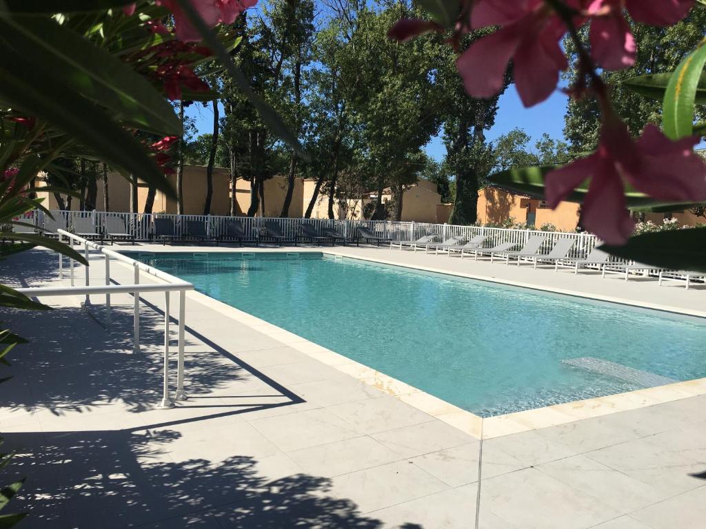 a swimming pool with white chairs and trees at Bastidon des Alpilles 11 in Saint-Rémy-de-Provence