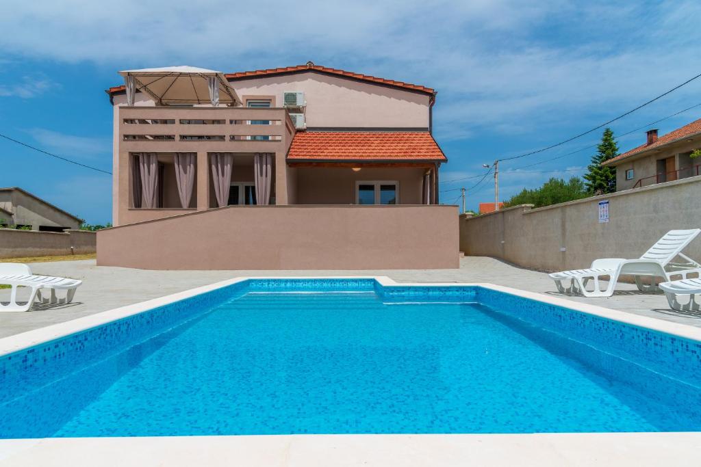 a swimming pool in front of a house at Apartmani Kržak in Nin