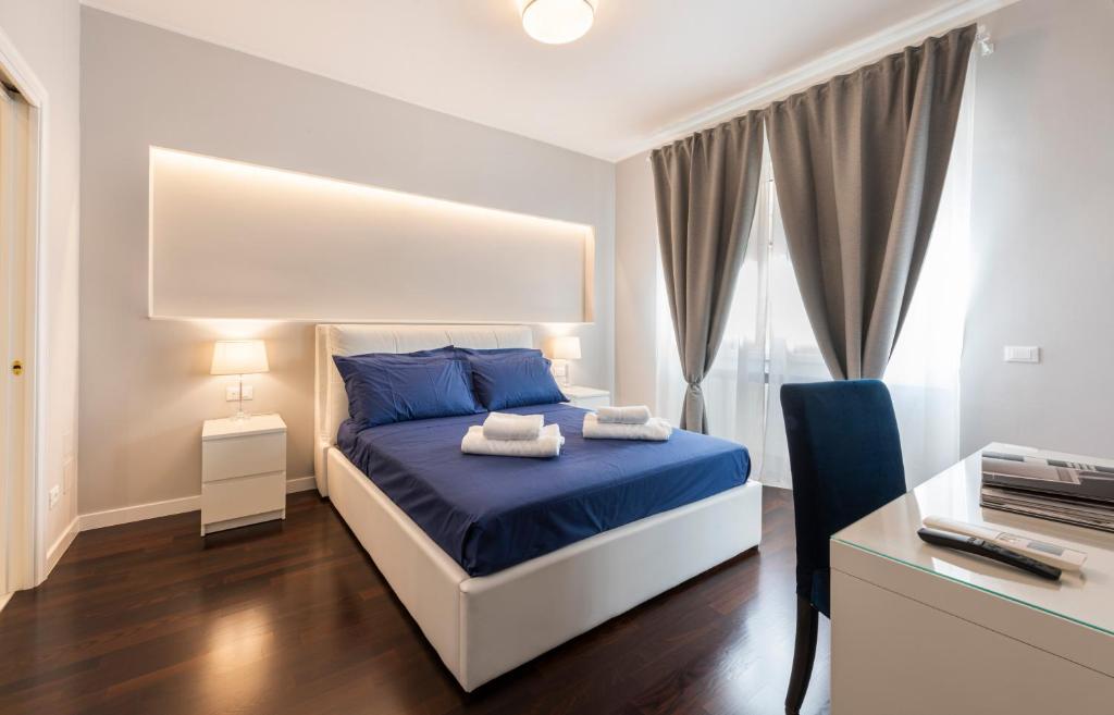 sypialnia z niebieskim łóżkiem i biurkiem z drukarką w obiekcie Ponte Vecchio Deluxe Apartments we Florencji