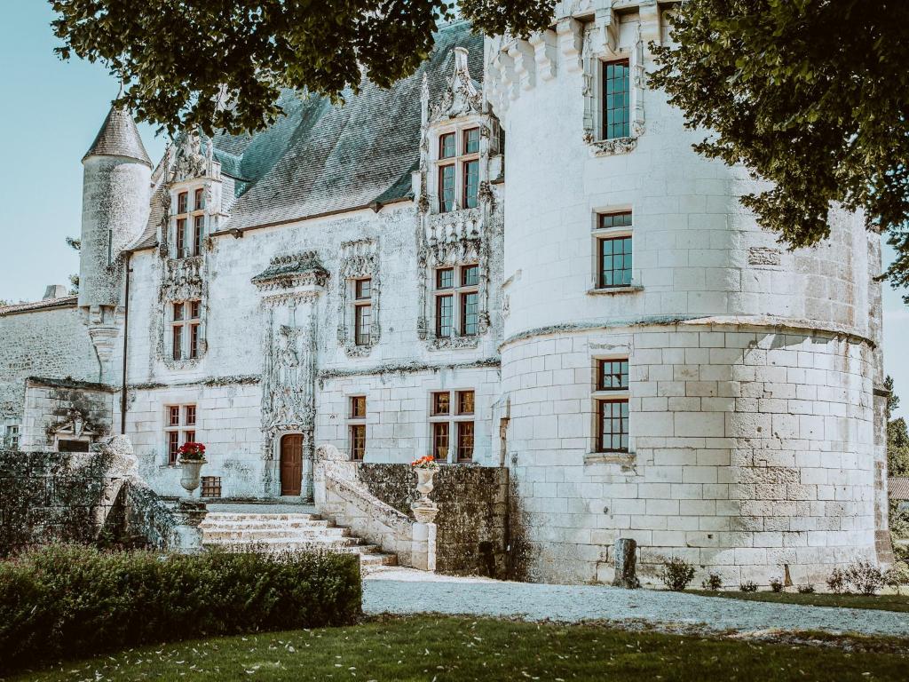 an old white castle with a staircase in front of it at Château de Crazannes in Crazannes