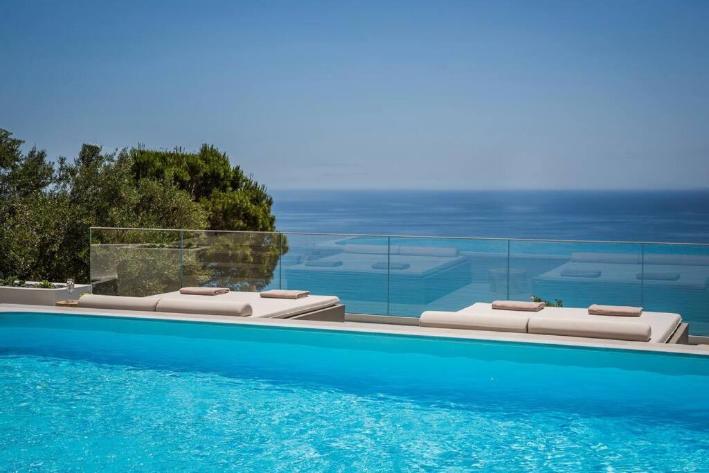 uma piscina com duas espreguiçadeiras ao lado em Lourdas White Villa em Cefalônia