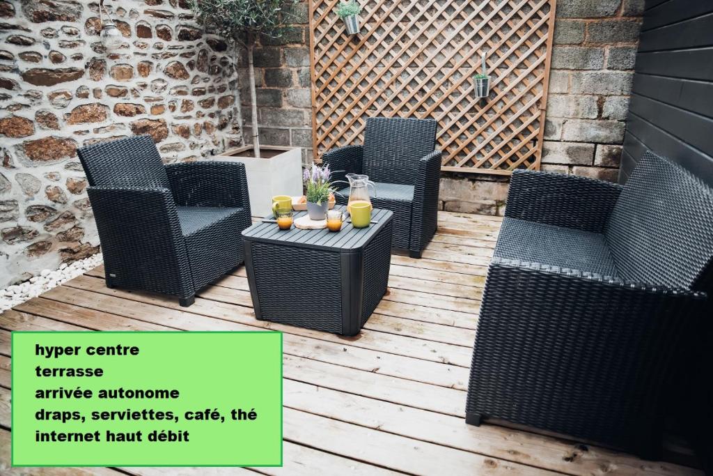 four wicker chairs and a table on a patio at Superbe appartement avec terrasse au calme in Ernée