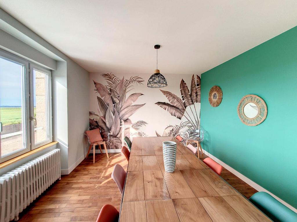 a dining room with a wooden table and blue walls at Au Mont Chez Vous #Jacuzzi et Vue Mont-St-Michel# in Huisnes-sur-Mer