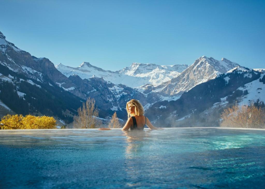 une femme dans une piscine à débordement dans les montagnes dans l'établissement The Cambrian, à Adelboden