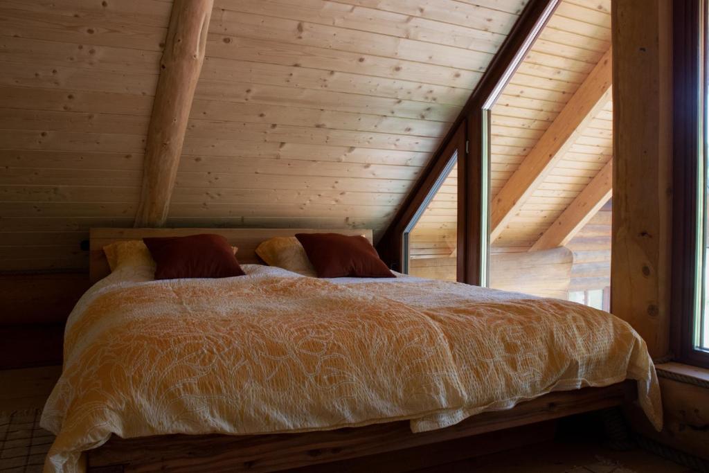 Bett in einem Zimmer mit Holzdecke in der Unterkunft Brunarica Biopark -Log house Biopark in Grosuplje