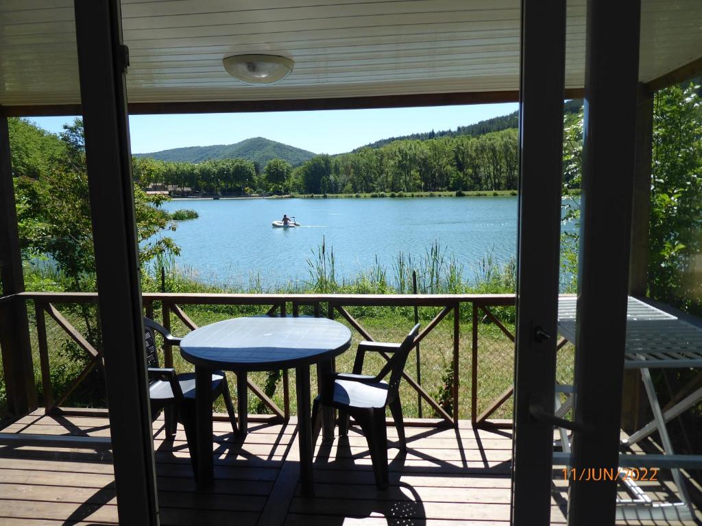 una mesa y sillas en un porche con vistas al lago en Camping Le Bouloc, en Ceilhes-et-Rocozels