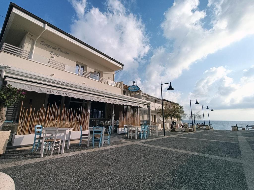 ein Gebäude mit Stühlen und Tischen vor dem Meer in der Unterkunft Borgo dei Pescatori in Capo Vaticano