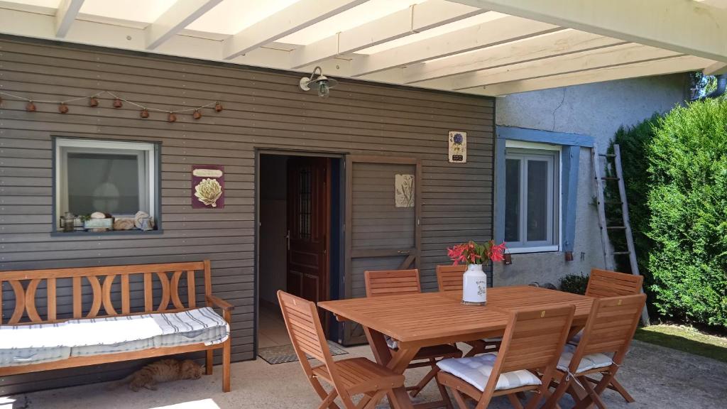 einen Holztisch und Stühle auf einer Terrasse in der Unterkunft La Taniere Douce in Soulaucourt-sur-Mouzon