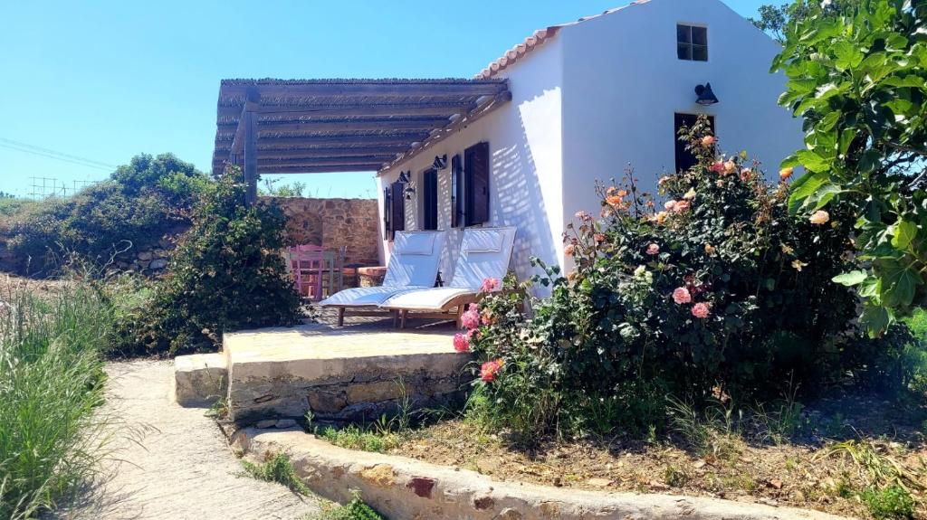 een wit huis met een bank en wat bloemen bij The pigeon House in Potamós