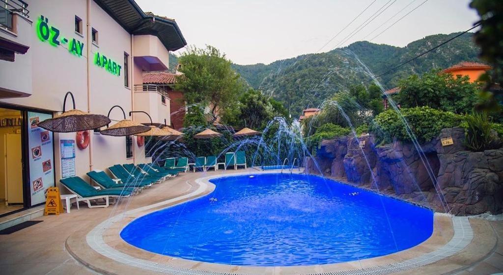 a swimming pool with a fountain in front of a building at Özay Apart Otel in Mugla