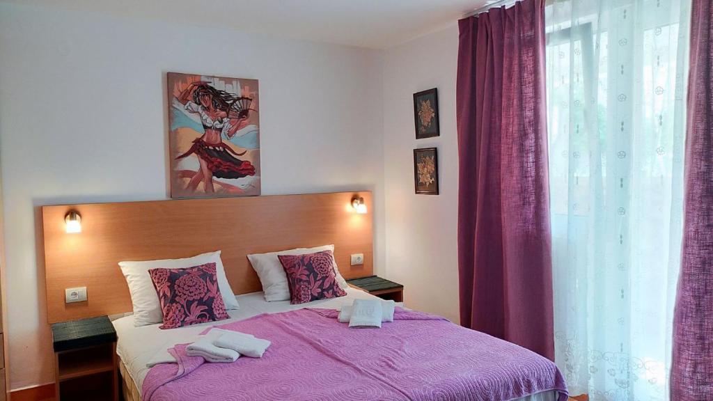 a bedroom with a purple bed with towels on it at Guesthouse Tri Palme in Bečići