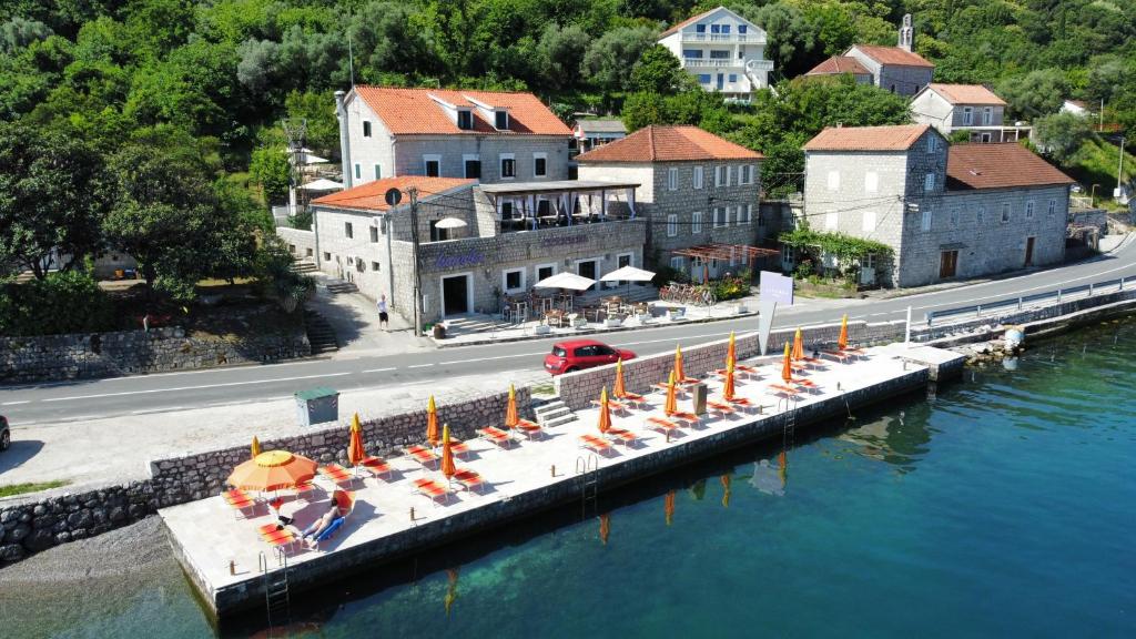 eine Gruppe von Stühlen und Sonnenschirmen auf einem Dock in der Nähe des Wassers in der Unterkunft Hotel Lavanda in Donja Kostanjica