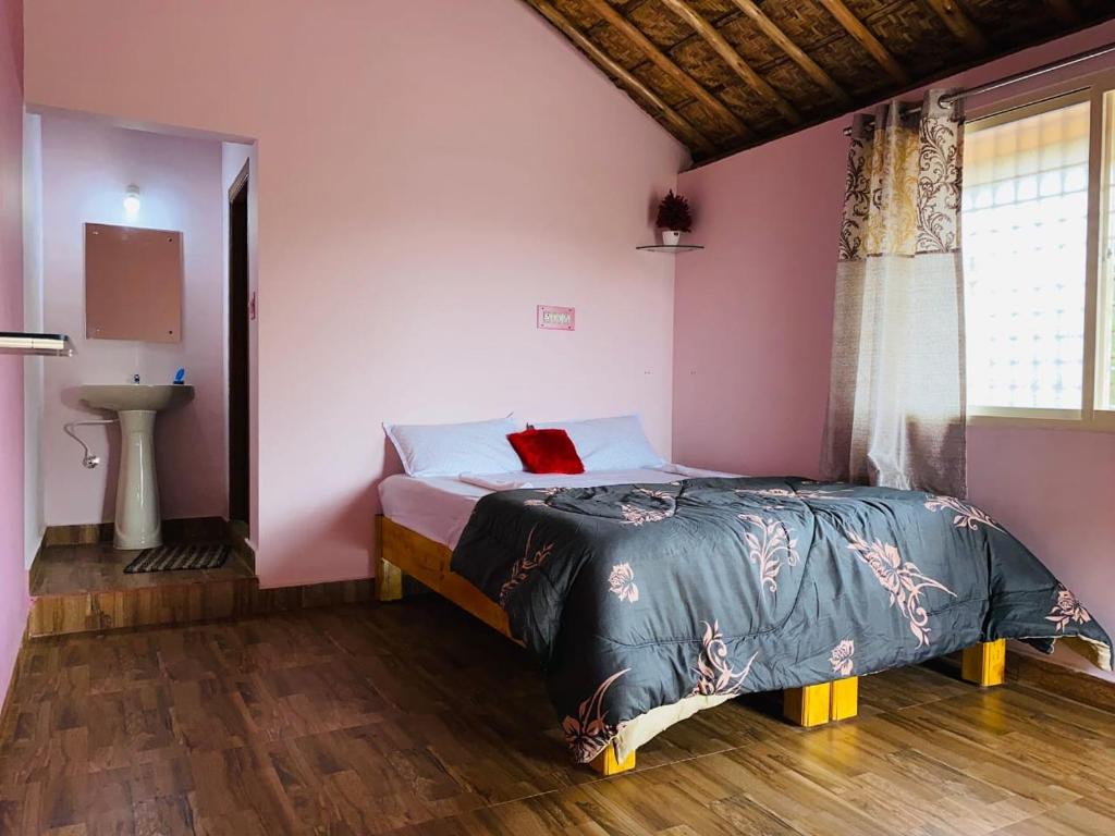 a bedroom with a bed in a room with pink walls at Prajwal home stay in Hampi